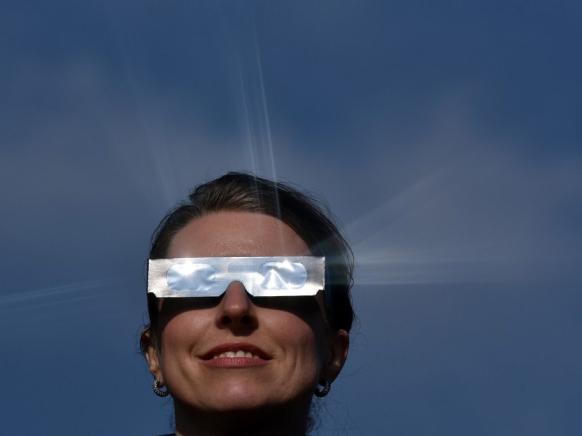 Femme observant une éclipse solaire en toute sécurité avec des lunettes de protection spéciﬁques en film argenté filtrant certifié